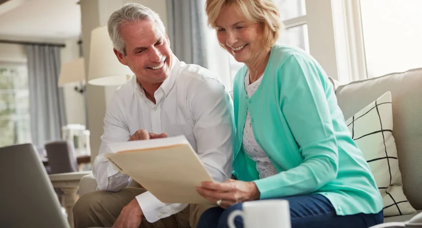 senior-couple-paperwork-laptop-sofa-with-discussion-smile-taxes-home-old-man-woman-computer-with-documents-compliance-reading-investment-report-with-finance-management